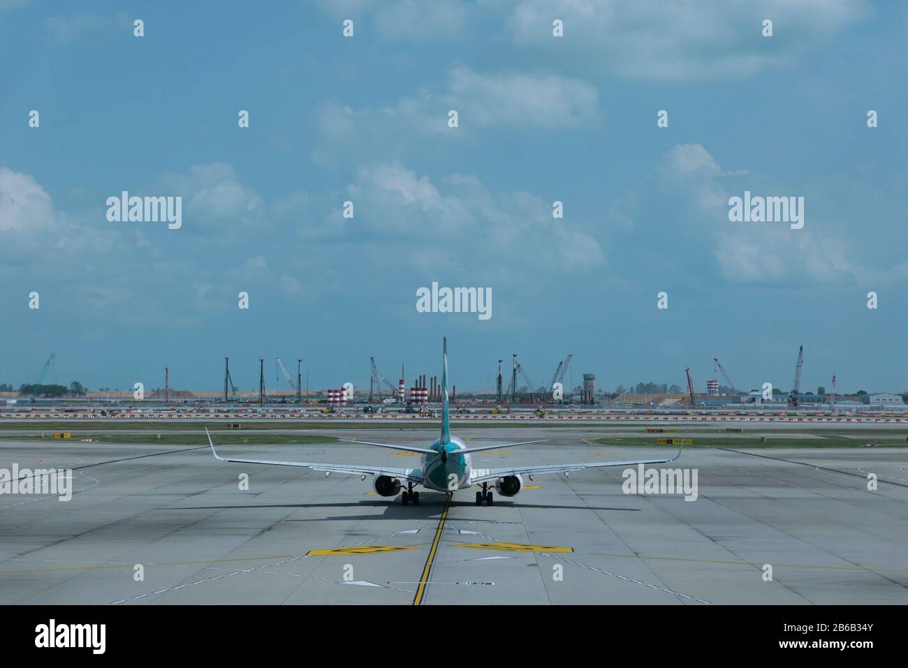 Flugzeug auf der Start- und Landebahn des Flughafens Singapur unter dramatischem Himmel Stockfoto