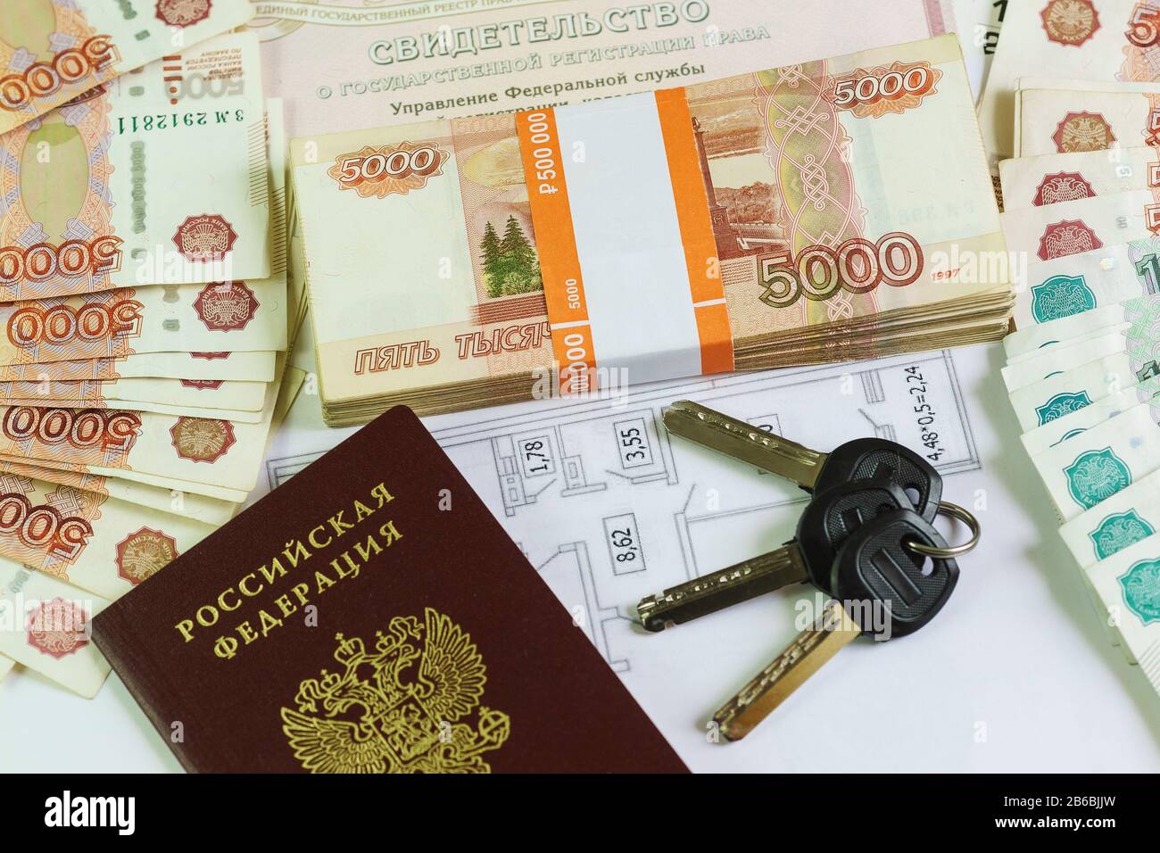 Beschriftung auf Russisch: Bescheinigung über die staatliche Registrierung von Immobilien. Reisepass, Plan und Schlüssel zum großen Teil russischen Geldes. Käuflich Stockfoto