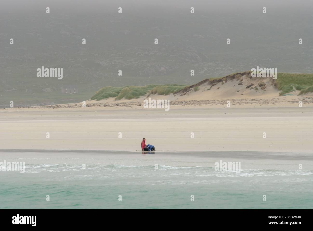 Mutter und Kind spielen an einem kalten windigen Tag an einem einsamen Strand auf der Insel Harris, Schottland. Stockfoto