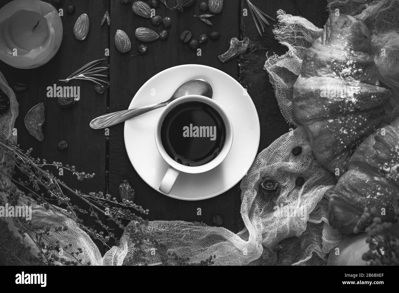 Tasse schwarzen Kaffee und Croissants auf dunklem, monochromen Hintergrund, Draufsicht. Flaches Lay aus Espresso und Cornettorollen auf dunklem rustikalem Tisch Stockfoto
