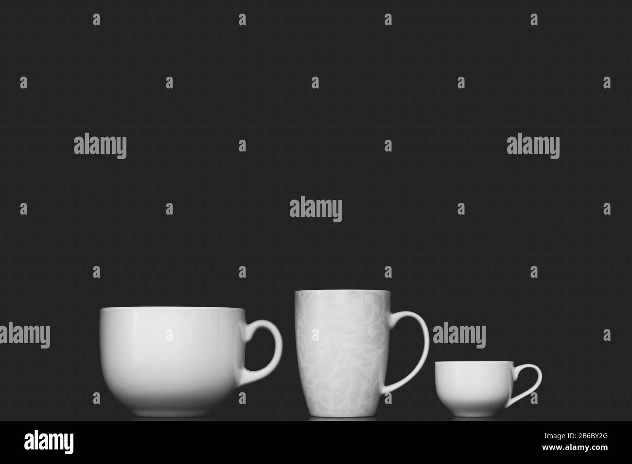 Drei verschiedene weiße Tassen im schwarzen Hintergrund Stockfoto