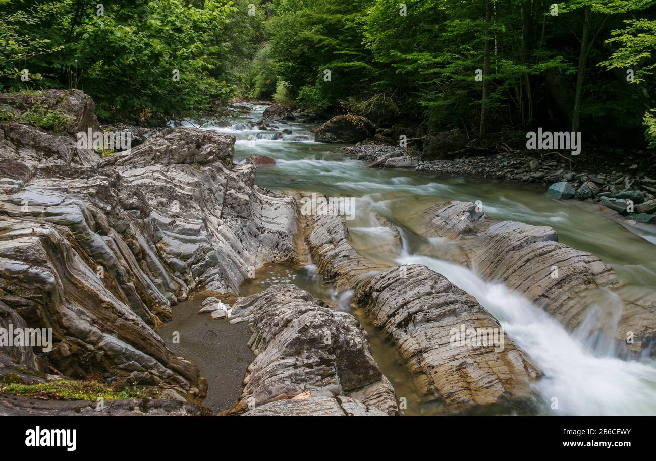 Bergwaldbach mit schnell fließendem Wasser und Felsen, lange Belichtung, Frühling. Stockfoto