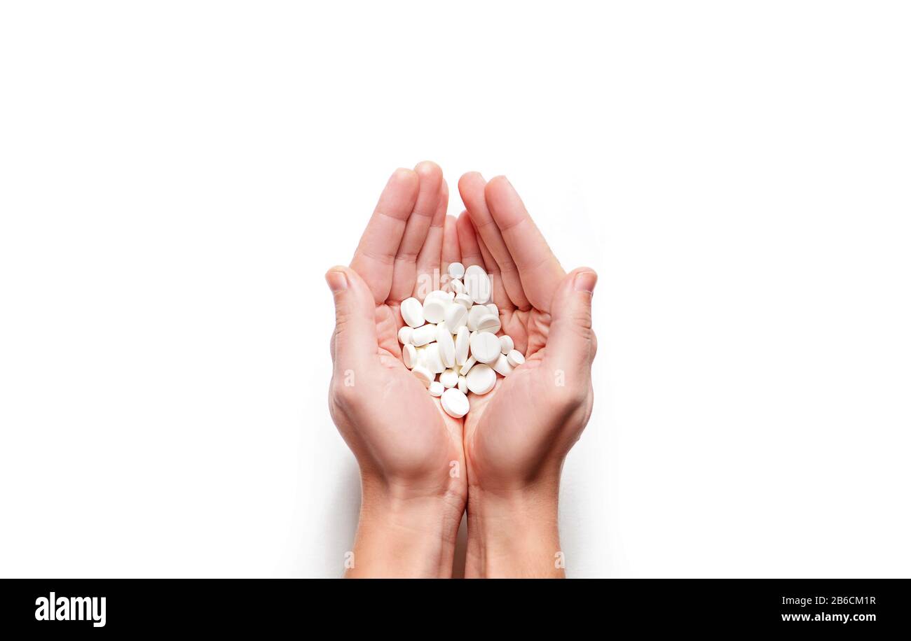 Man Hände mit einer Handvoll weißer Pillen isoliert auf weißem Hintergrund. Kopierbereich. Stockfoto