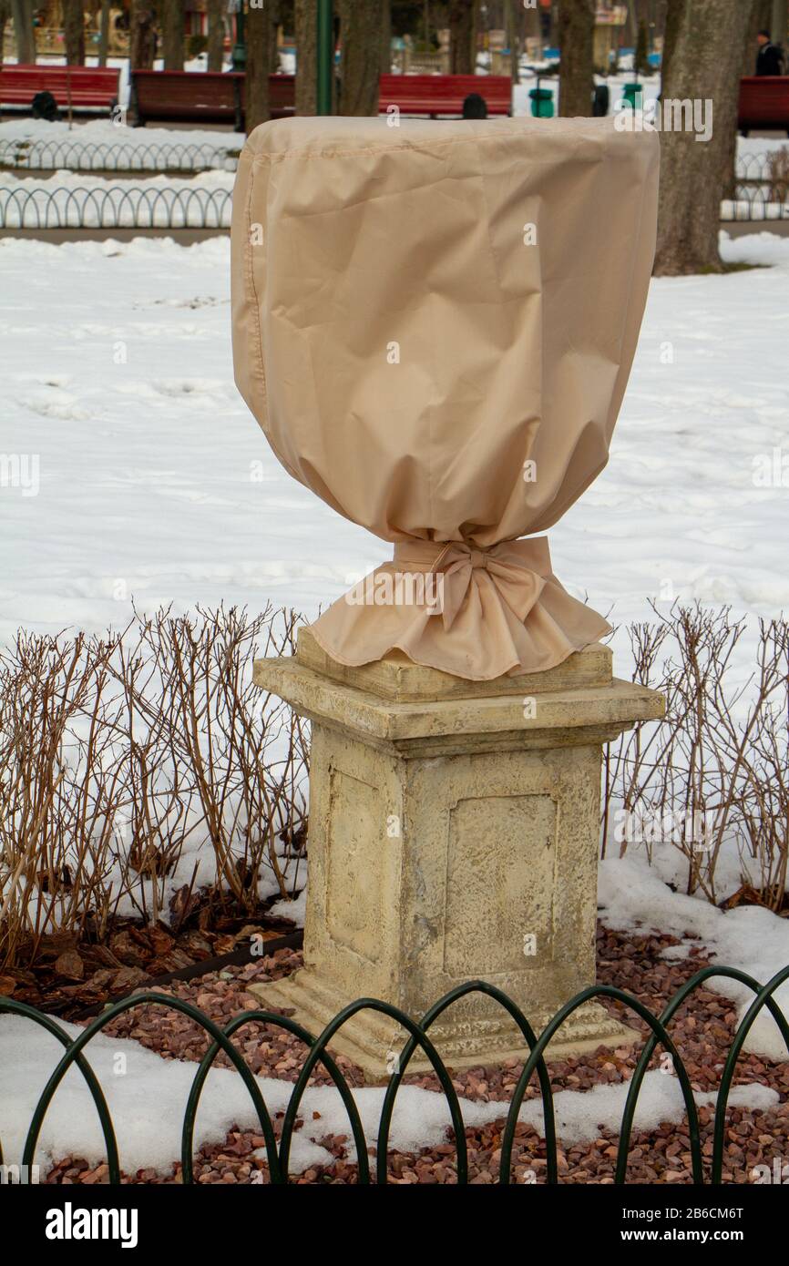 Pflanzen im Park sind mit speziellem Material bedeckt, sie bereiten Pflanzen für die Überwinterung vor und schützen die Umwelt Stockfoto