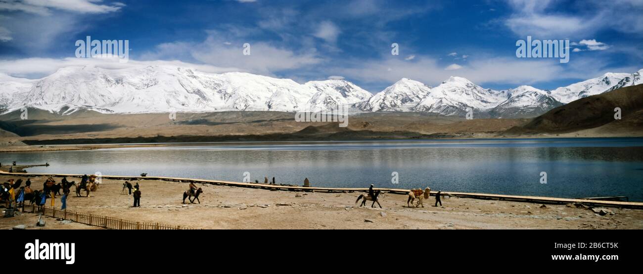 Touristen reiten am See, Muztagh Ata, Karakul Lake, Provinz Xinjiang, China Stockfoto