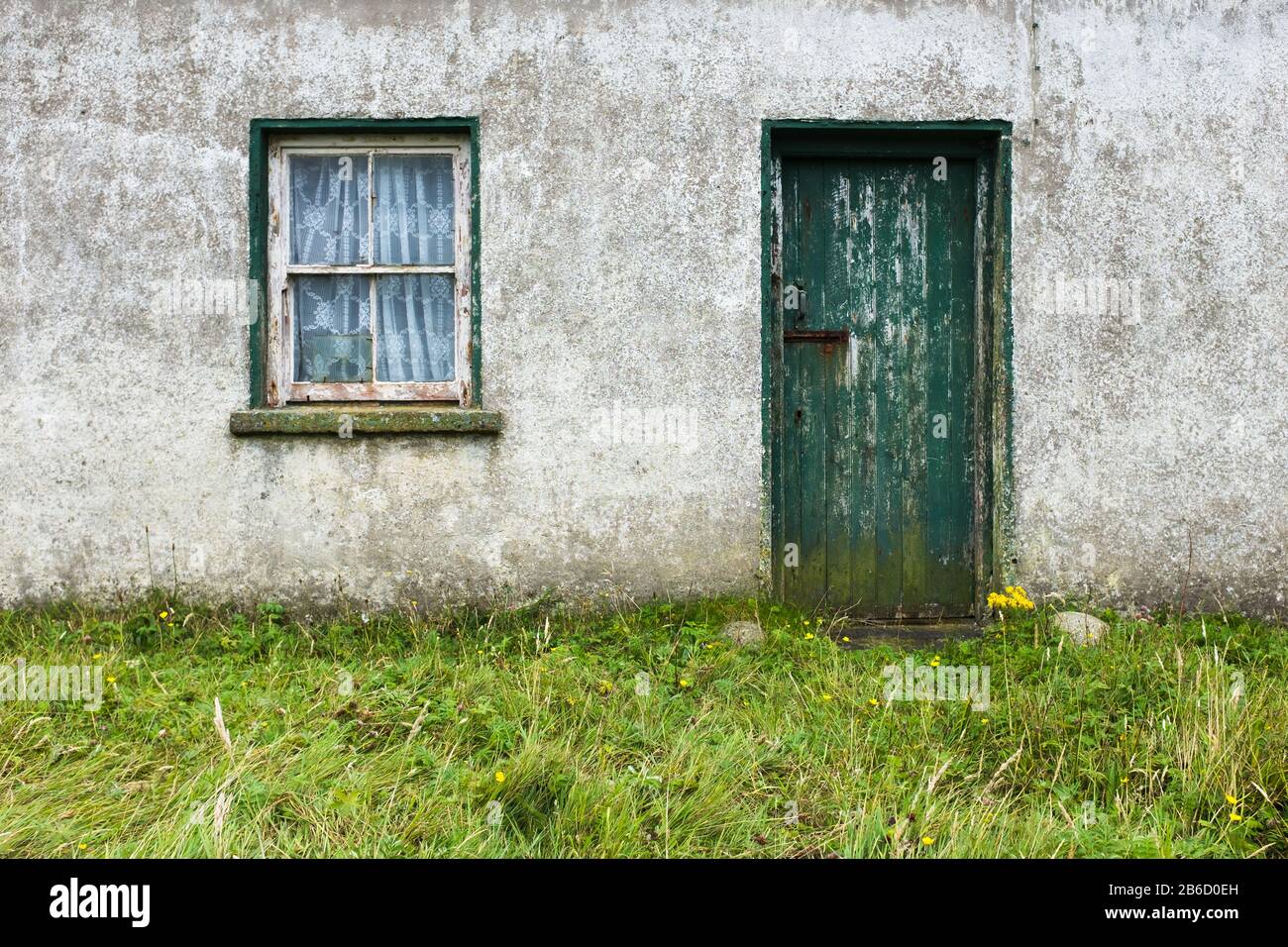 Runter irisches Cottage mit grüner Tür und Fenster mit abgebrochenem Lack Stockfoto