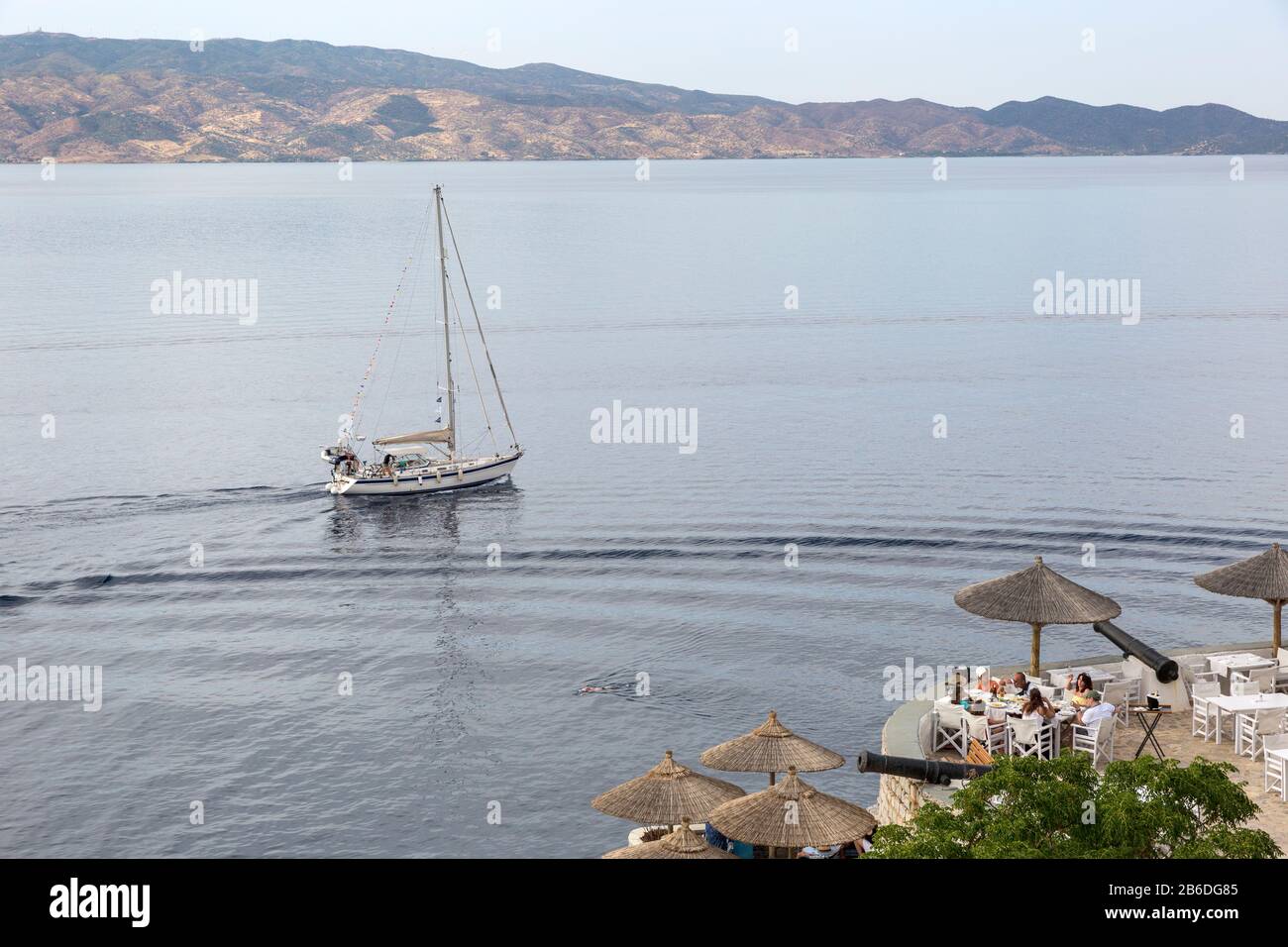 Segelboot und Leute speisen in einem Restaurant im Freien auf der Insel Hydra, Griechenland Stockfoto