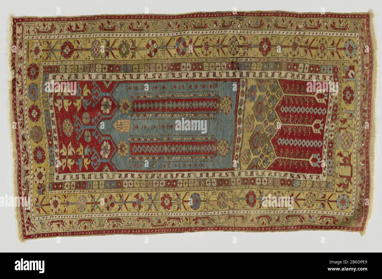 Gebetskrug, genannt Kolommenbidkleed mit Bodenplatte und Jahr, Ladik Bidkleed, z. B. kolommenbidkleed, met benedenpaneel en (onduidelijk) jaartal, LaDIK. Middenveld: Lichtblauwe mihrab met driedelige, in het miden hogere topgevel, een jaartal (1211? = 1796?), zwevende kolommen en slierten motieven. OP Rode zwikken staan vier anjelieren in geel met blauw en geel met wit. Driedubbel zickzagpaneel van oker en bruin, ingrijpend in een rood benedenpaneel met drie afhangendtulpen in wit, Stockfoto