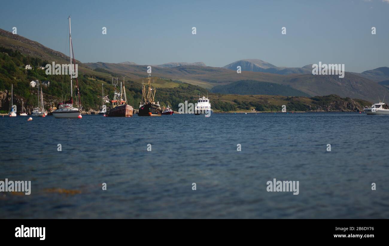 Schöner sonniger Tag am Hafen in Ullapool, Scottish Highlands, Schottland, Großbritannien; Malerisches Dorf Und Loch Broom, Unterhalb von Mountain Range Stockfoto