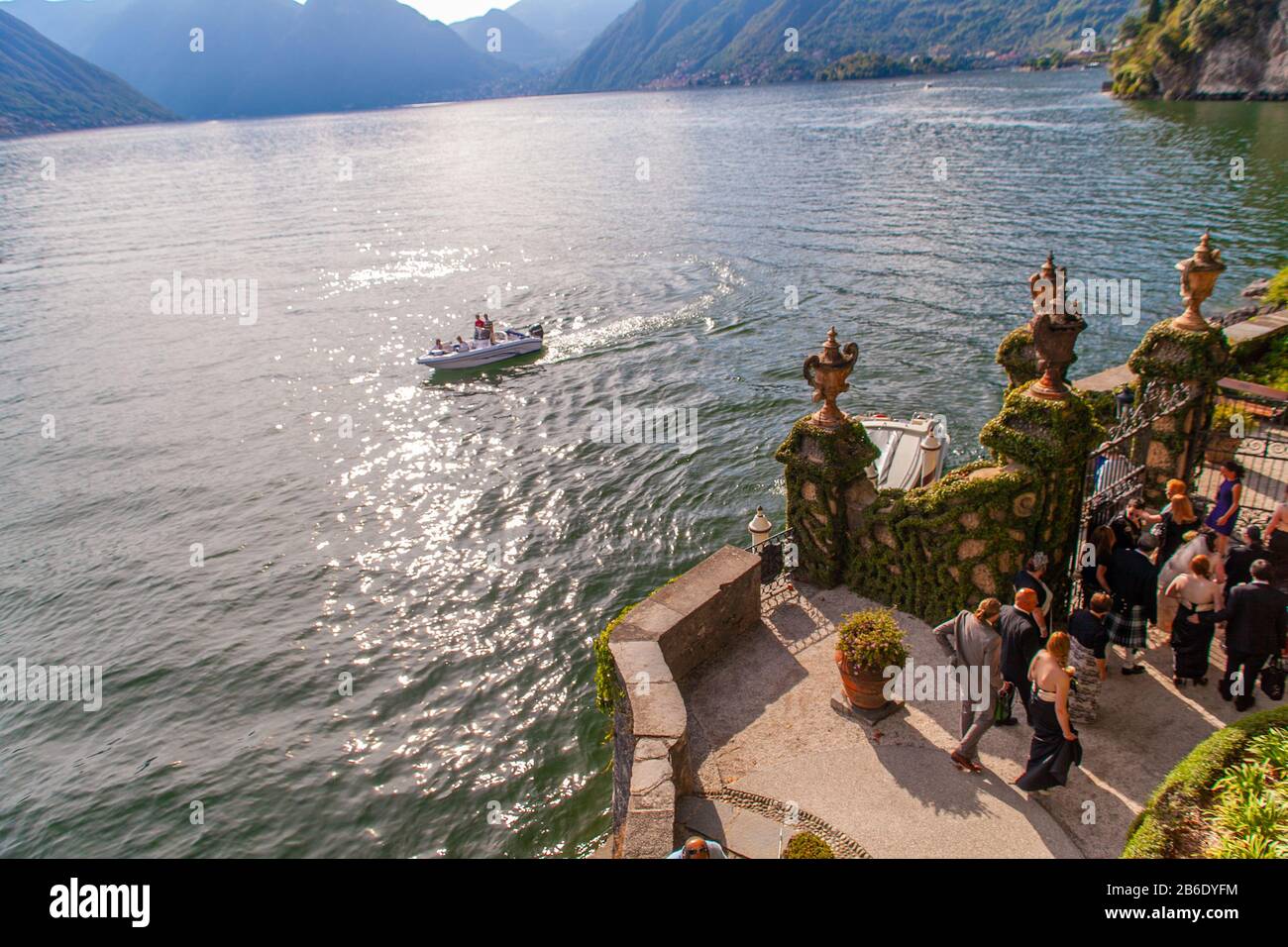 Menschen, die bei Sonnenuntergang eine Hochzeitsfeier in der Villa del Balbianello am Comer See, Lombardei, Italien, feiern Stockfoto