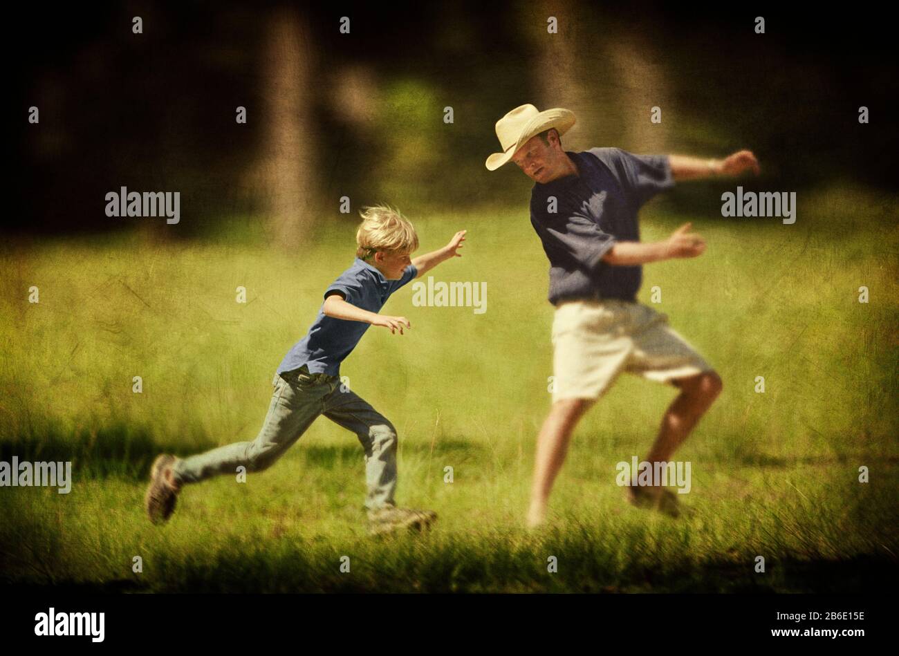 Ein Junge, der versucht, seinen Vater auf den grünen Wiesen zu fangen. Stockfoto