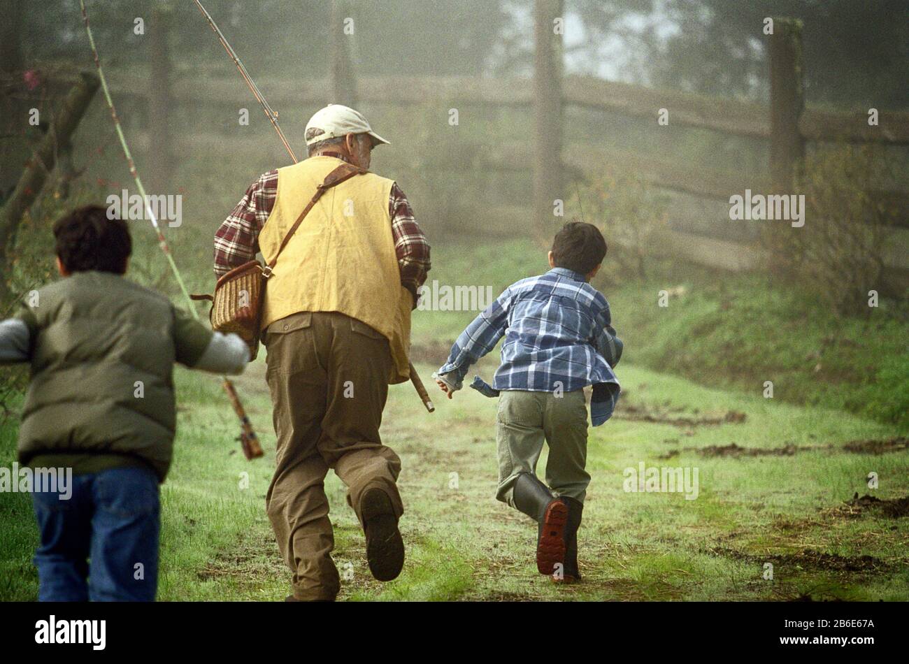 Vater und seine Söhne laufen zum Fischfang durch den Rasenplatz. Stockfoto