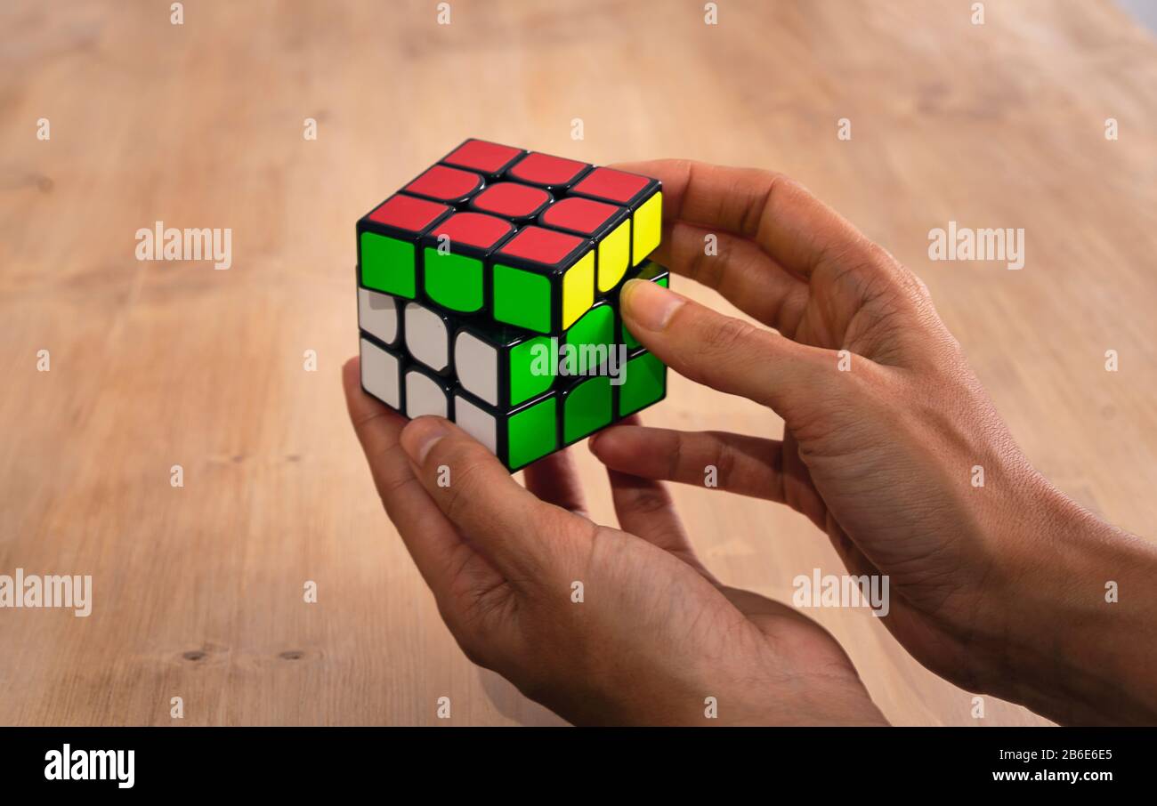Rubik's Cube Intelligenz Spielzeug Lösung in einer Hand, in einem Holz Tisch Stockfoto