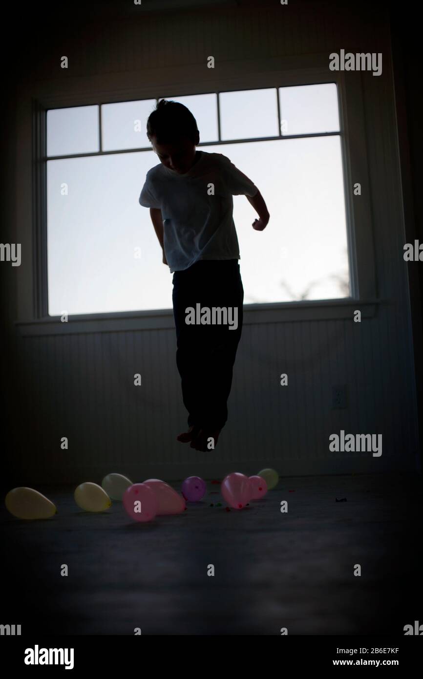 Kleiner Junge springt in einem Raum mit Luftballons. Stockfoto