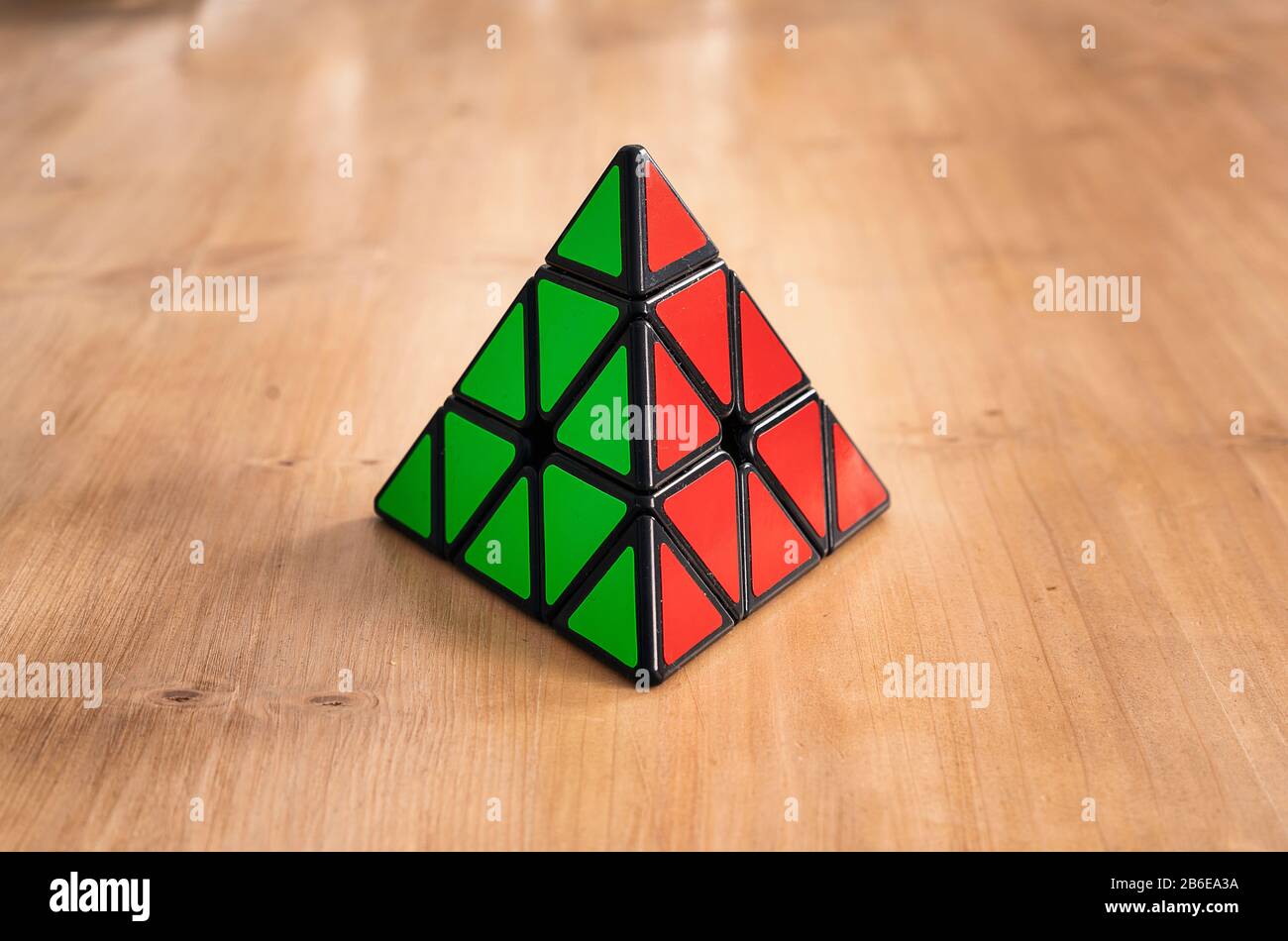 Rubik pyramidaler Würfel in einem Holztisch gelöst Stockfoto