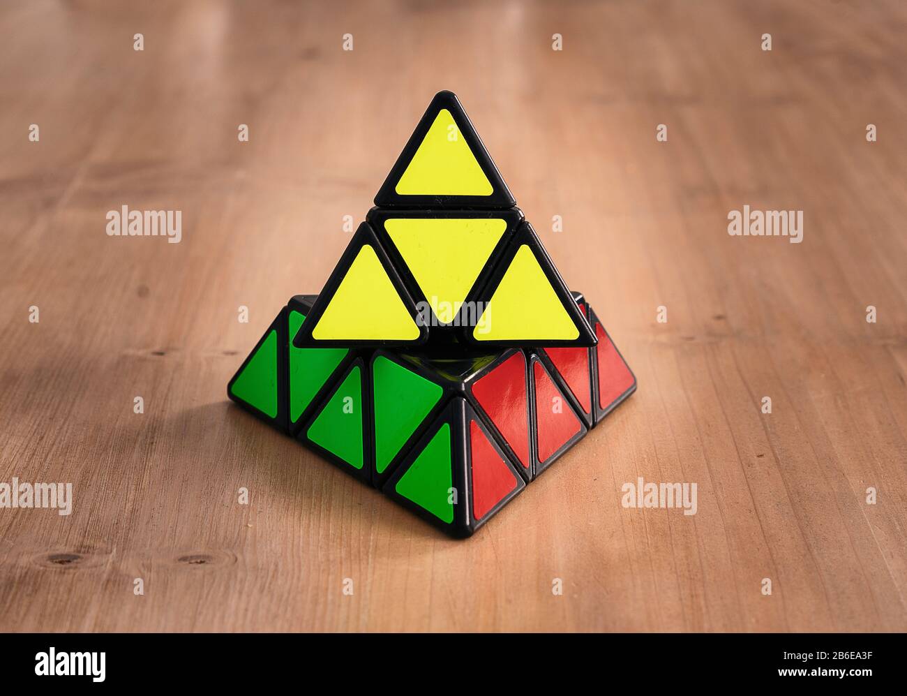 Rubik pyramidaler Würfel in einem Holztisch gelöst Stockfoto