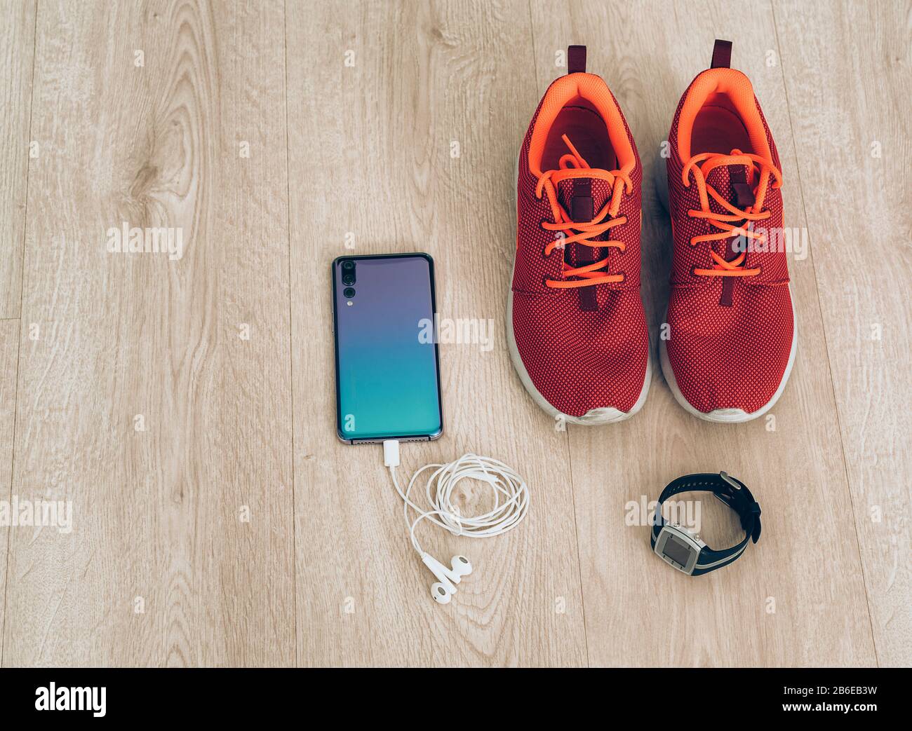 Coole Runner Sneaker mit Smartphone, Ohrhörer und fitbit Sportuhr. Bereit für Training, gesundes Leben Stockfoto