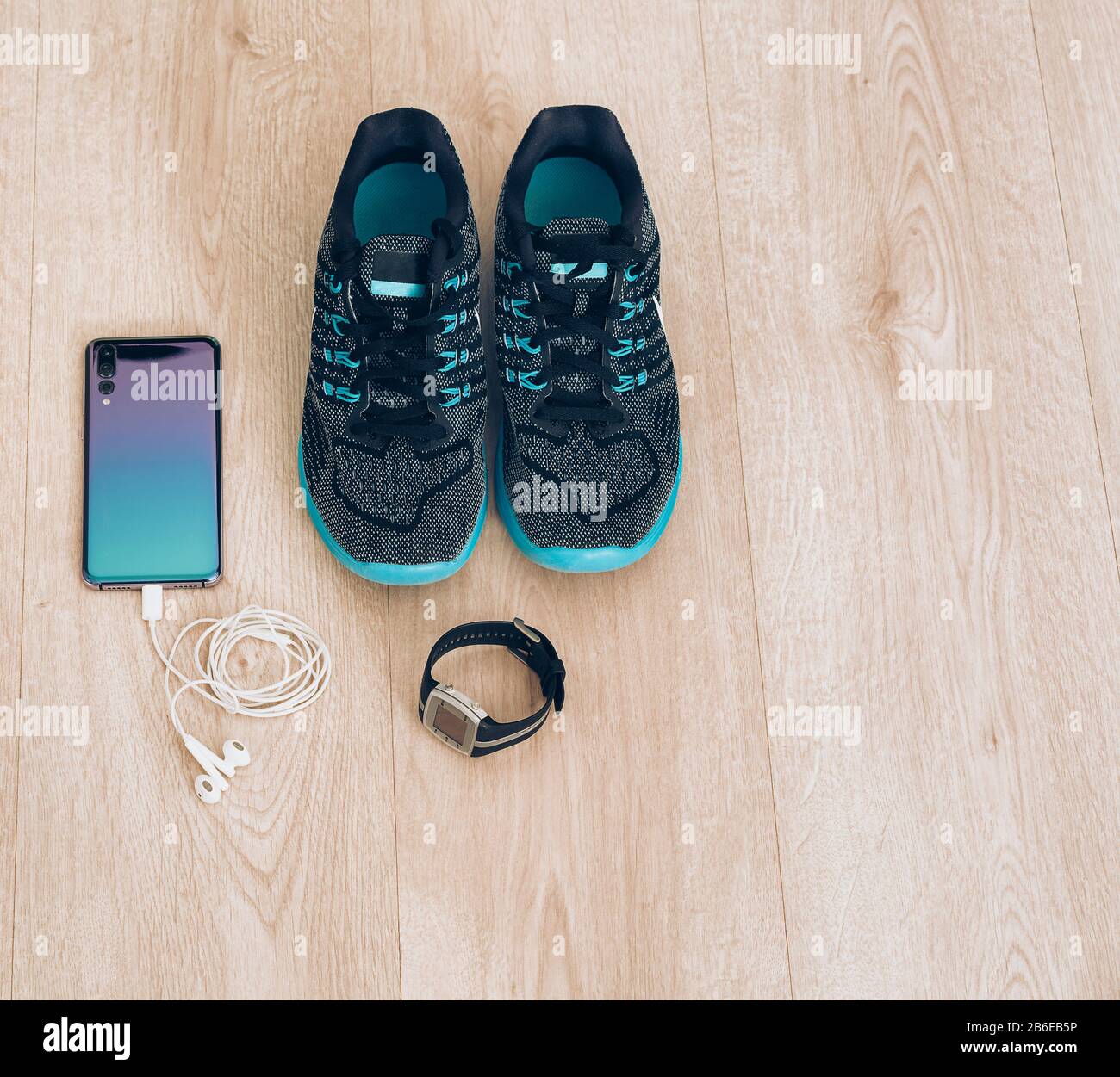 Coole Runner Sneaker mit Smartphone, Ohrhörer und fitbit Sportuhr. Bereit für Training, gesundes Leben Stockfoto