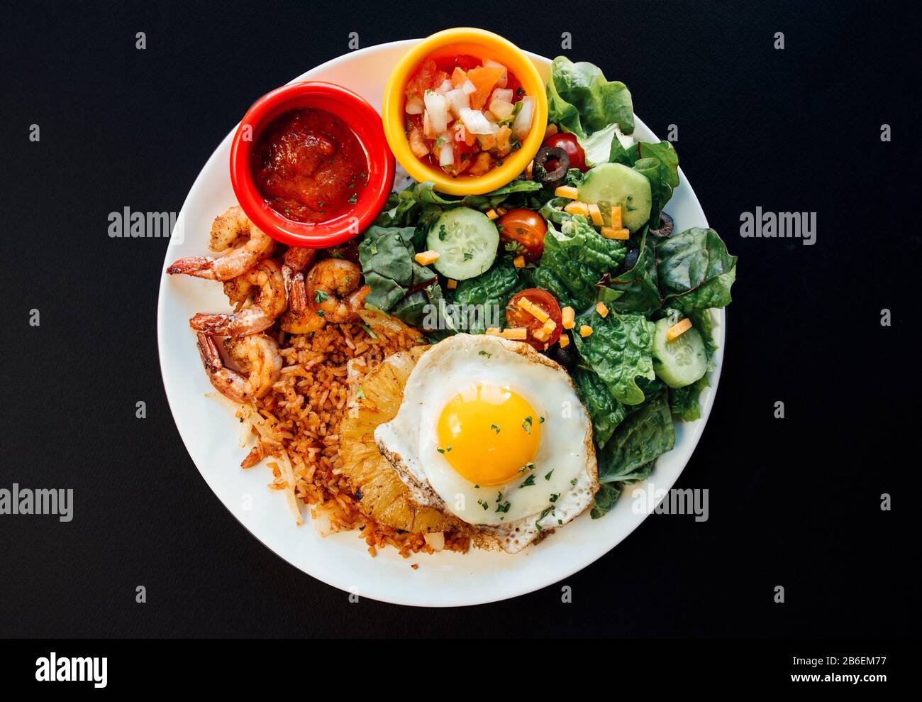 Asiatischer Ananas gebratener Reis mit verschiedenen Gemüsen auf weißem Teller und schwarzem Hintergrund Stockfoto