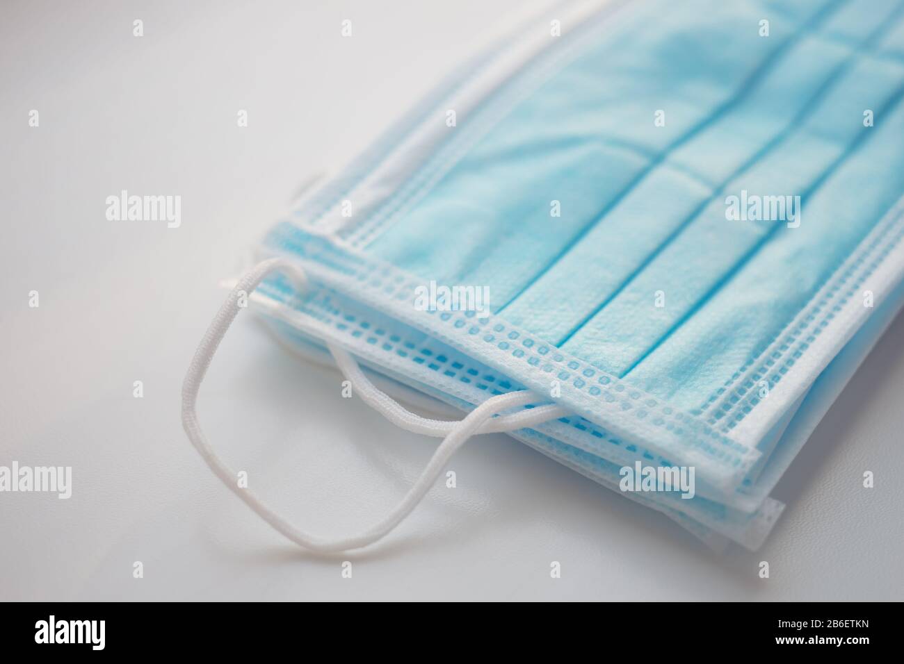 Blaue medizinische Gesichtsmasken auf dem weißen Tisch. Seitenansicht. Stockfoto