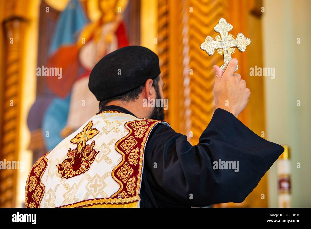 Priester des Heiligen Vaters, der während der heiligen Zeremonie ein goldenes Kreuzsymbol hält Stockfoto