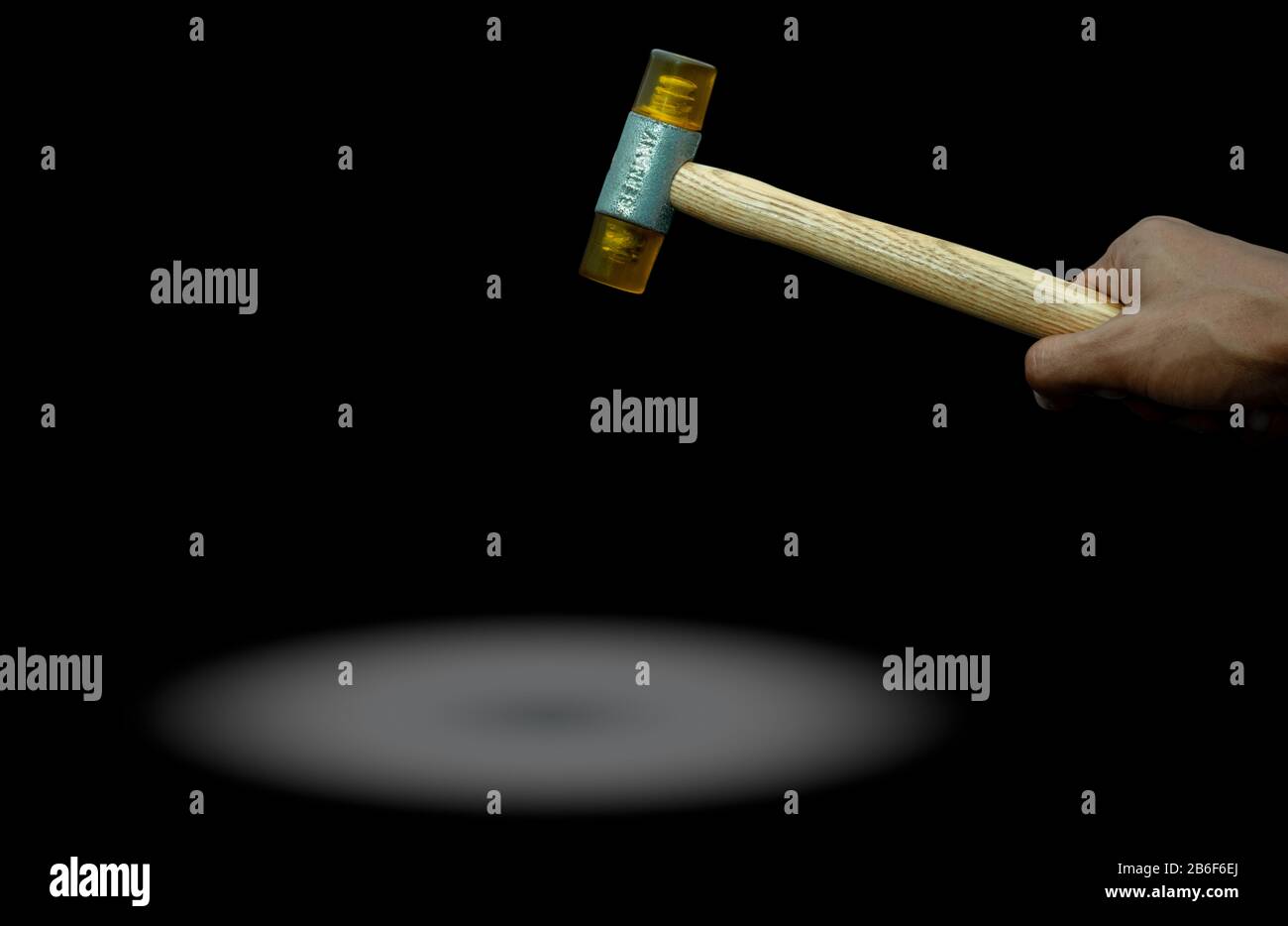 Hand des Mannes, der Kunststoffhammer isoliert auf dunklem Hintergrund hält. Holzgriff aus Kunststoffhammer für die Hand des männlichen Arbeiters. Hammerkopf aus weichem Material Stockfoto