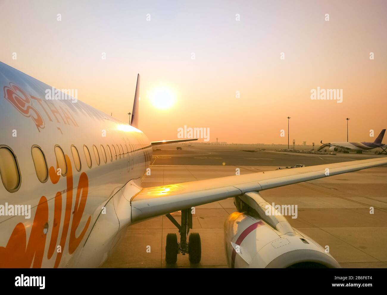 Bangkok, THAILAND - FEBRUAR 2020: Thai Smile Airways. Passagierflugzeug am Flughafen Suvarnabhumi geparkt. Nahaufnahme Flugzeugflügel mit goldenem Sonnenaufgang Himmel Stockfoto