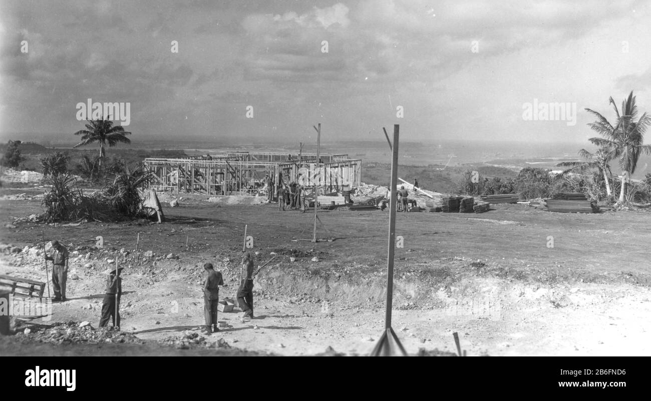 Seabees on Guam, # 3, 1944. Vier Männer davor bereiten einen groben Straßenplan vor, während im Hintergrund fast ein Dutzend Seabees den Rahmen und die Wände eines Gebäudes errichten. Diese Seabees bauen Straßen und Gebäude für die Gebäude der CINCPAC-Offiziere. Um meine zugehörigen Vintage-Bilder zu sehen, suchen Sie nach Prestor Vintage WW II Stockfoto
