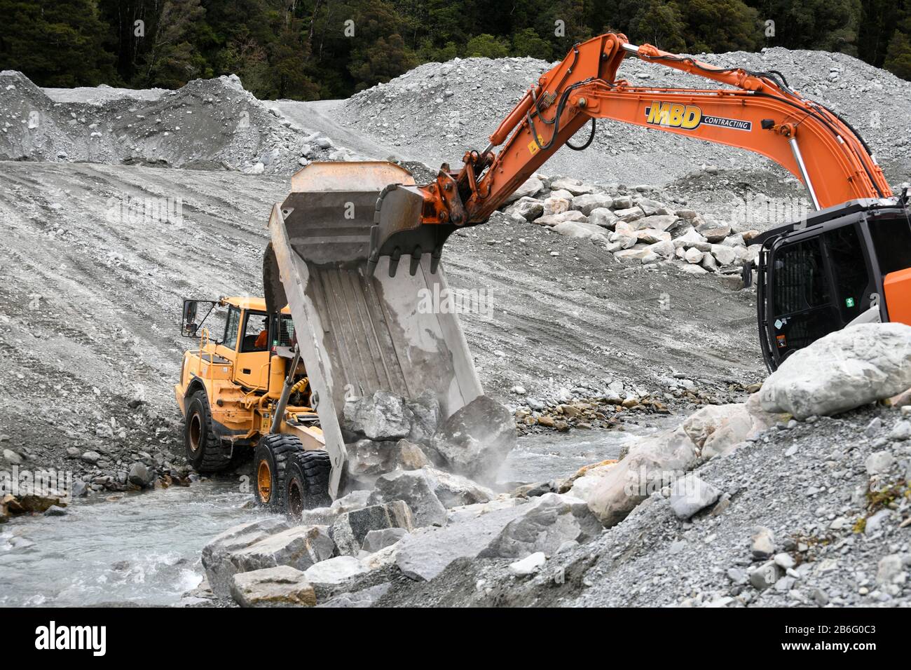 OTIRA, NEUSEELAND, 19. SEPTEMBER 2019: Ein Tip-Truck stumpft eine Last von Felsen, um an einem Fluss an der Westküste etwas oberhalb eines Eisenbahnbrids die Flutwassersteuerung zu schaffen Stockfoto