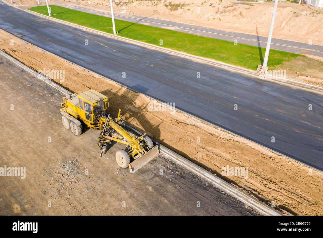 Straßengrader auf Straßenbaustelle. Maschinen arbeiten am Bau neuer Straße. Luftbild Stockfoto