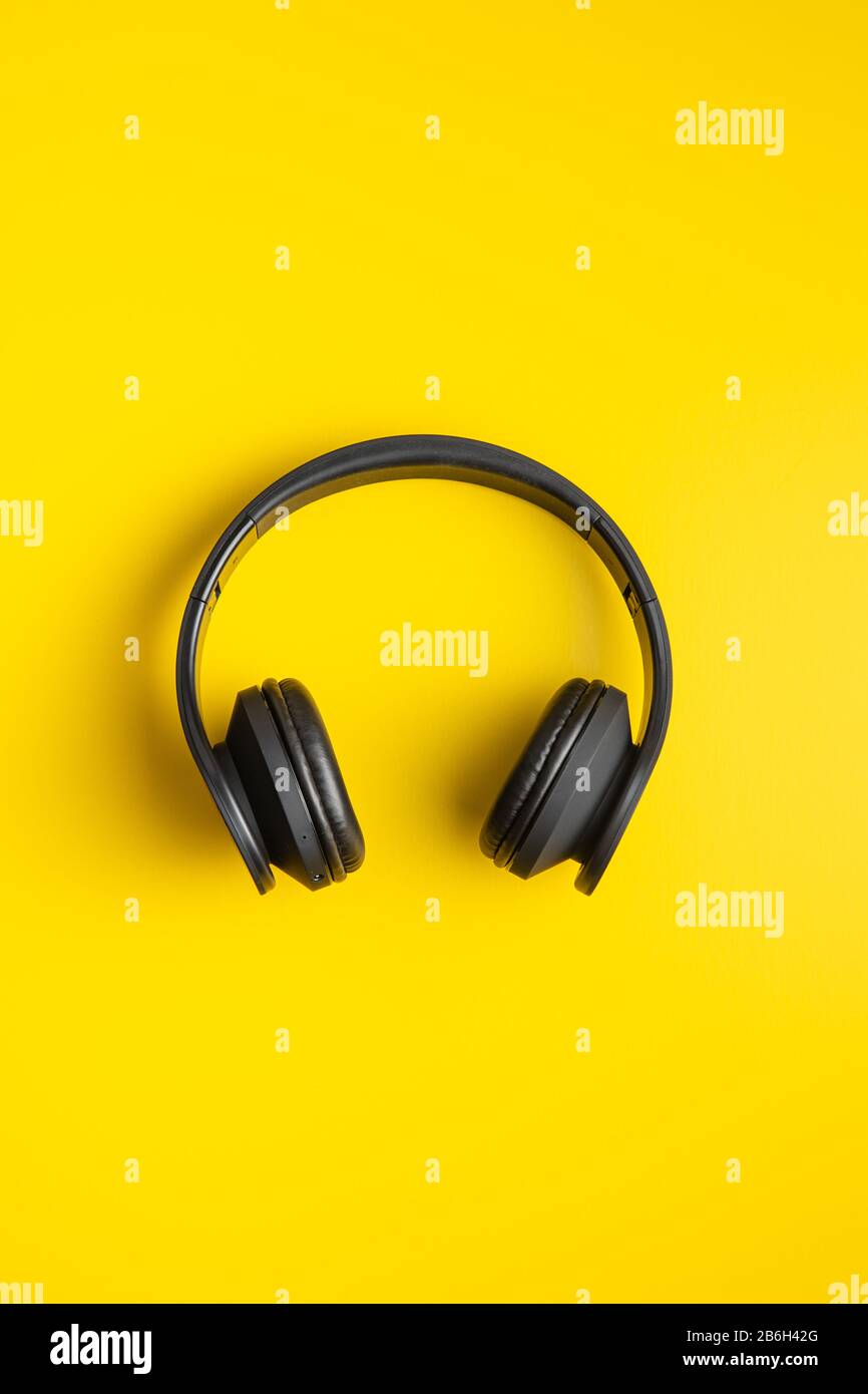 Schwarze kabellose Kopfhörer auf gelbem Hintergrund. Draufsicht. Stockfoto