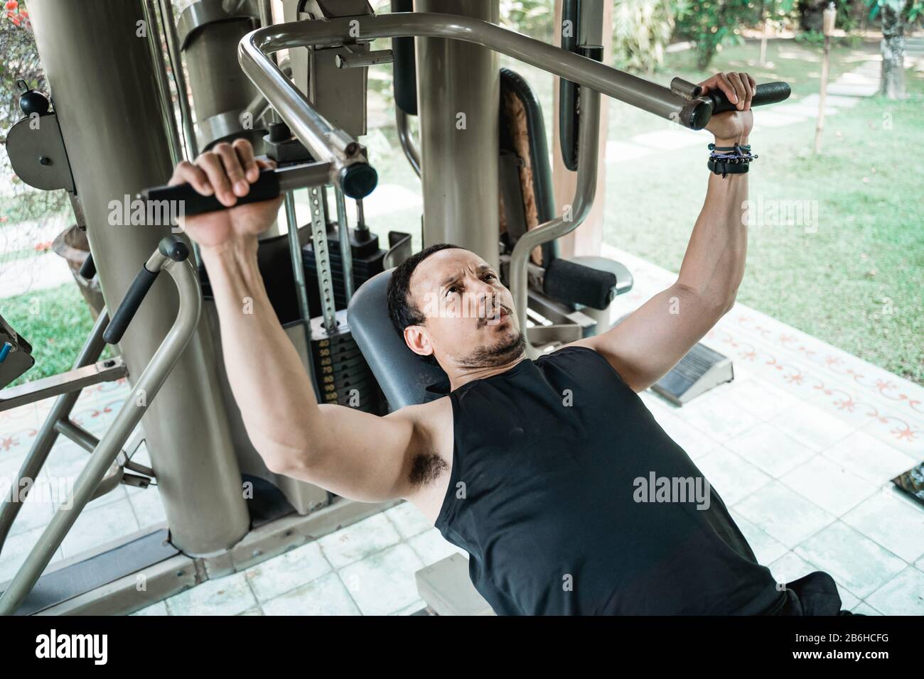 Asian man Workout mit Pressmaschine im Fitnessstudio Stockfoto