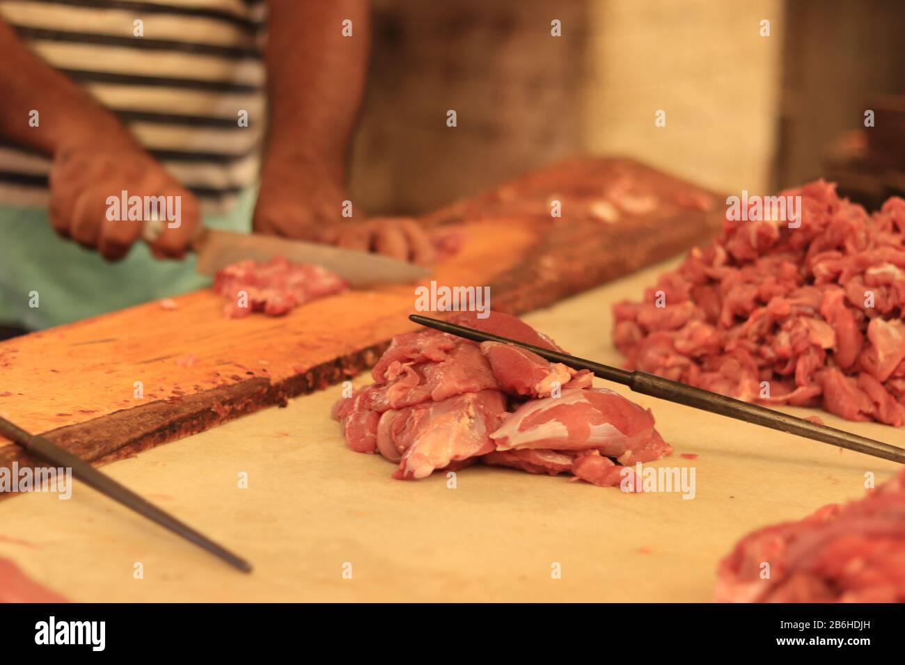 Metzger schneidet Fleisch auf Schneidebrett Stockfoto