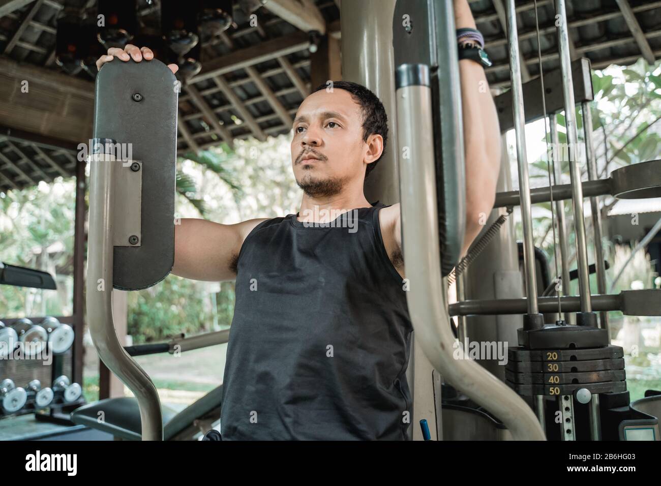 Asiatischer junger Mann, der Brustübungen mit pec-Deckmaschine im Firness House macht Stockfoto