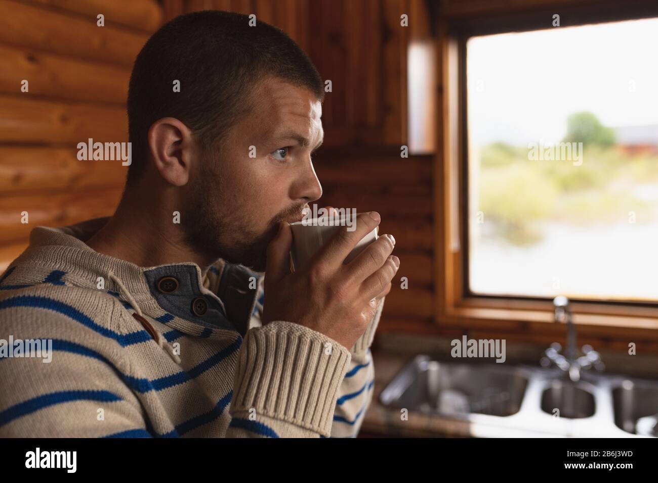 Kaukasischer Mann trinkt in einem warmen Becher Stockfoto