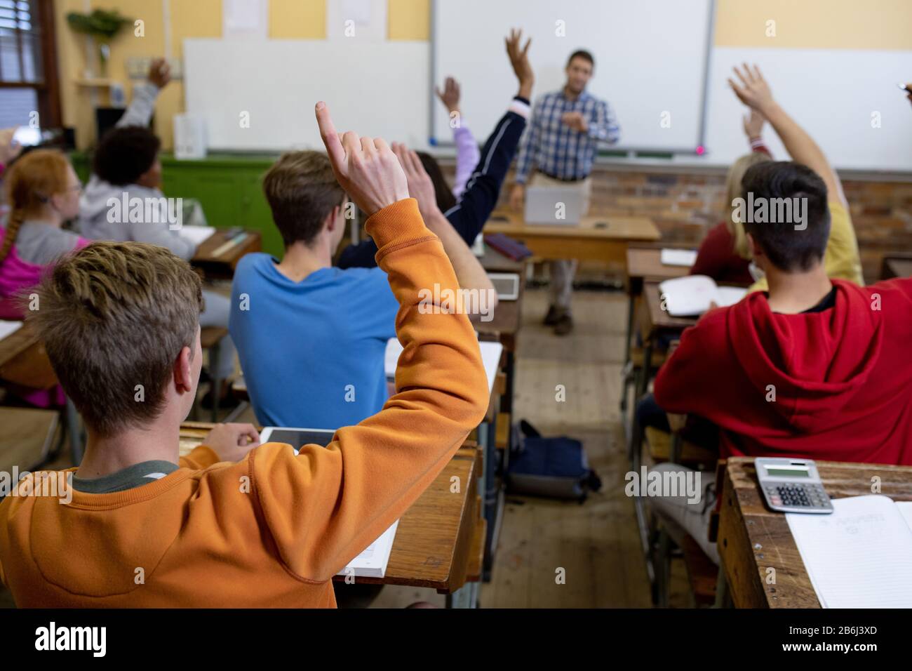 Rückansicht der Kursteilnehmer, die ihre Hände in der Klasse heben Stockfoto