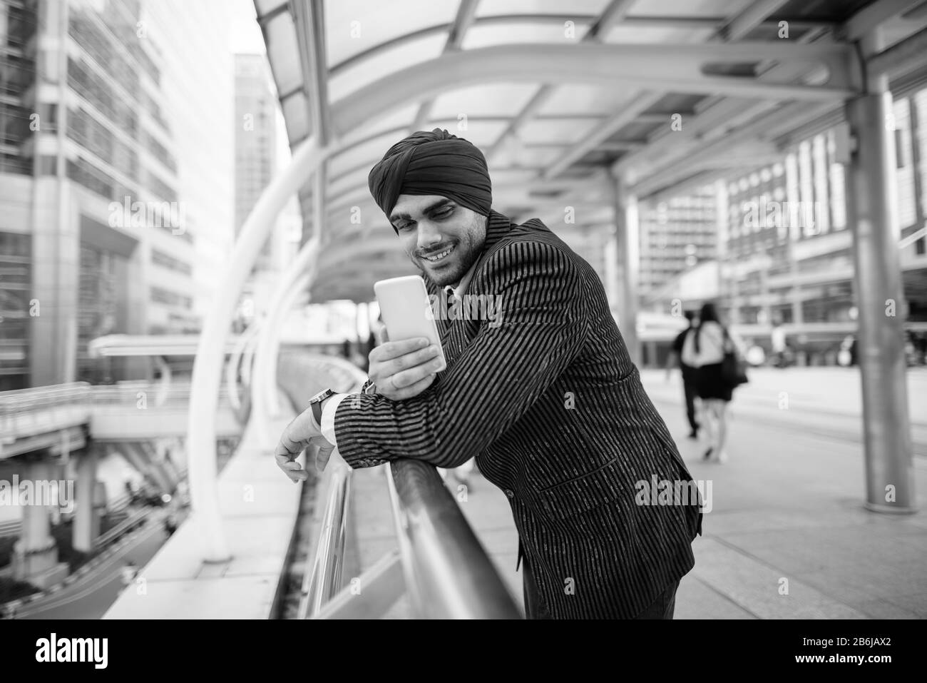 Fröhlicher junger, gutaussehender indischer Sikh-Geschäftsmann, der Turban in der Stadt trägt Stockfoto