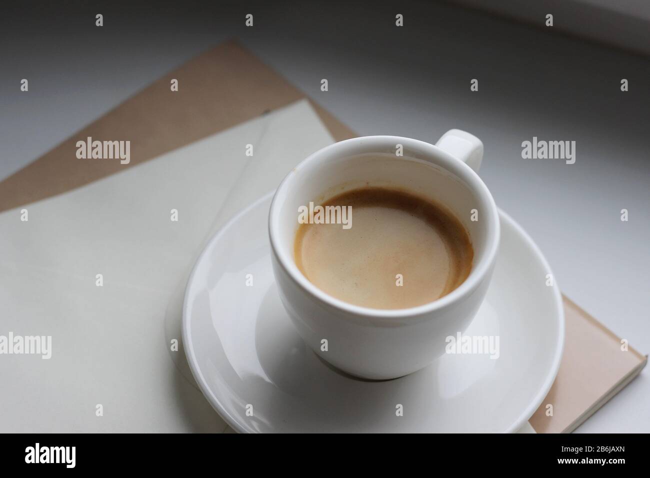 Eine Tasse Espresso auf weißem Hintergrund mit Notizbuch und Dokumenten. Frühstücksgetränk Am Morgen. Stockfoto