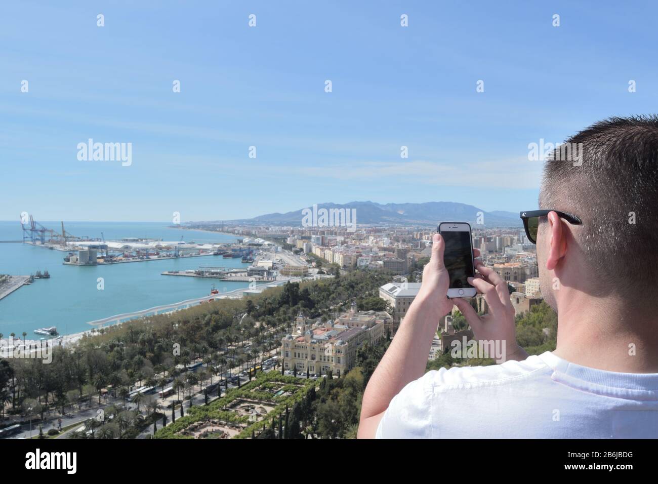 Tourist in Gibralfaro Aussichtspunkt, der Foto mit einem Handy von Malaga Hafen macht Stockfoto