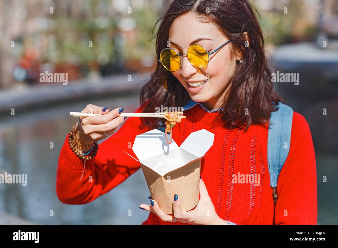 Asiatische Frau, die Straßennahrung aus dem Papierkästchen zum Mitnehmen in Hongkong im Freien isst Stockfoto