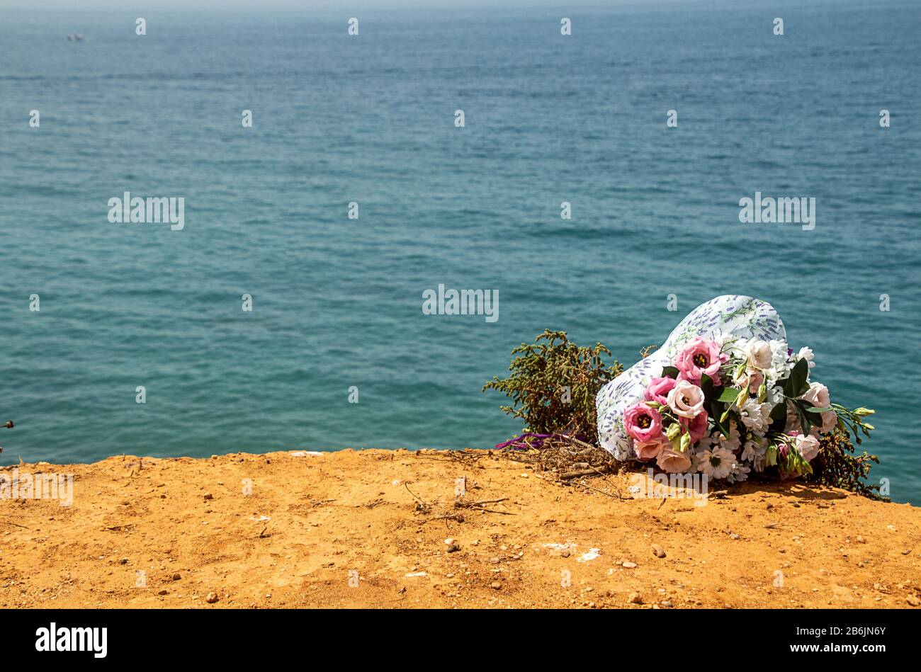 Beerdigung Blumen am Strand. Blumenstrauß am Doom Place, Erinnerung, Atlantischer Ozean, spanischer Seashoore. Kopieraum, Bestattungszeichen und Kondolenzkarte Stockfoto