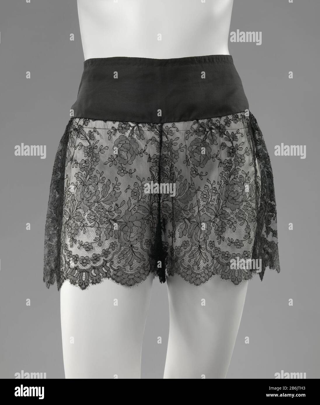 Directoire of Black Silk and Chantilly Spitzenmaschine Directoire van zwarte zijde en machinale Chantily kant. Modell: Gladde Tailleband traf auf sluiting Middenachter Tür Middel van drie kleine glanzende knauf. Versiering: Klokkende pijpen van een strook machinale Chantilly kant; geschulpt aan de onderkant. Hersteller : Vervaardiger: AnoniemPlaats Herstellung: België dating: CA. 1920 - ca. 1930 Material: Geheel: Zijde pijp: Kant (Materiaal) knoop: Kunstof Techniek: Chantilly-kant Abmessungen: Tailleband: L 10 cm. × b 40 cm Pijp: 28 cm. × b 35 cm. Stockfoto