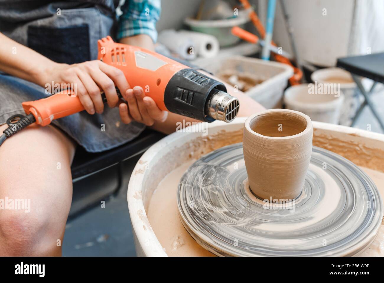 Eine Frau trocknet während einer Werkstatt eine nasse Tonware auf dem Töpferrad Stockfoto