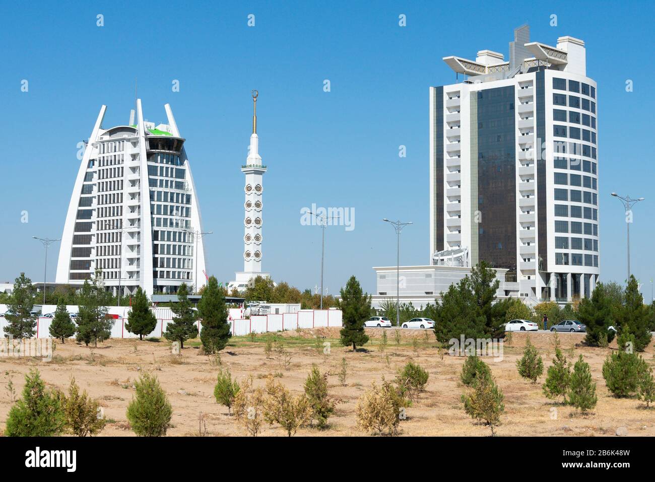 Zwei Gebäude aus weißem Marmor mit dem Verfassungsdenkmal zwischen Aschgabat, Turkmenistan. Regierungsgebäude aus weißem Marmor. Stockfoto