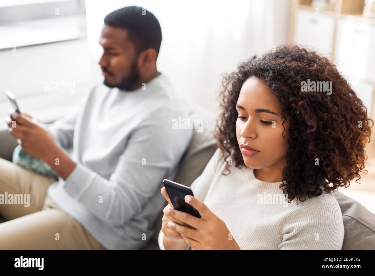 Technologie-, Internet- und Personkonzept - afro-amerikanisches Paar mit Smartphone zu Hause Stockfoto