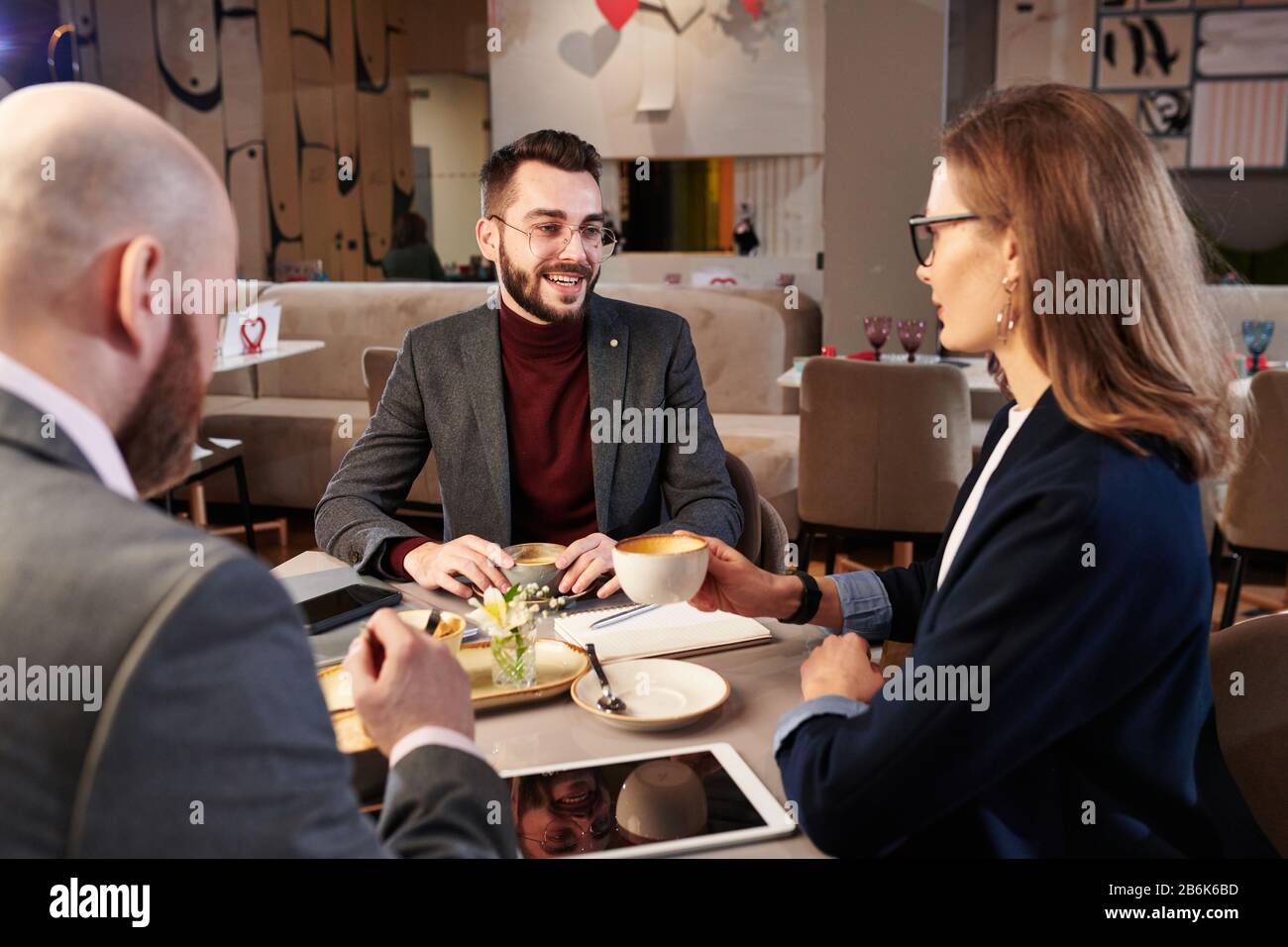 Eine Gruppe moderner Geschäftspartner, die Kaffee trinken und neue Kampagnen zur Umsatzsteigerung diskutieren Stockfoto