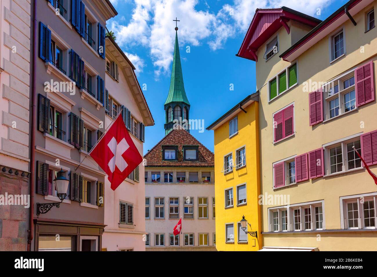 Schweizer Fahne schwenkt, Kirche und bunte Hausfassaden in Der Altstadt von  Zürich, der größten Stadt der Schweiz am sonnigen Tag Stockfotografie -  Alamy