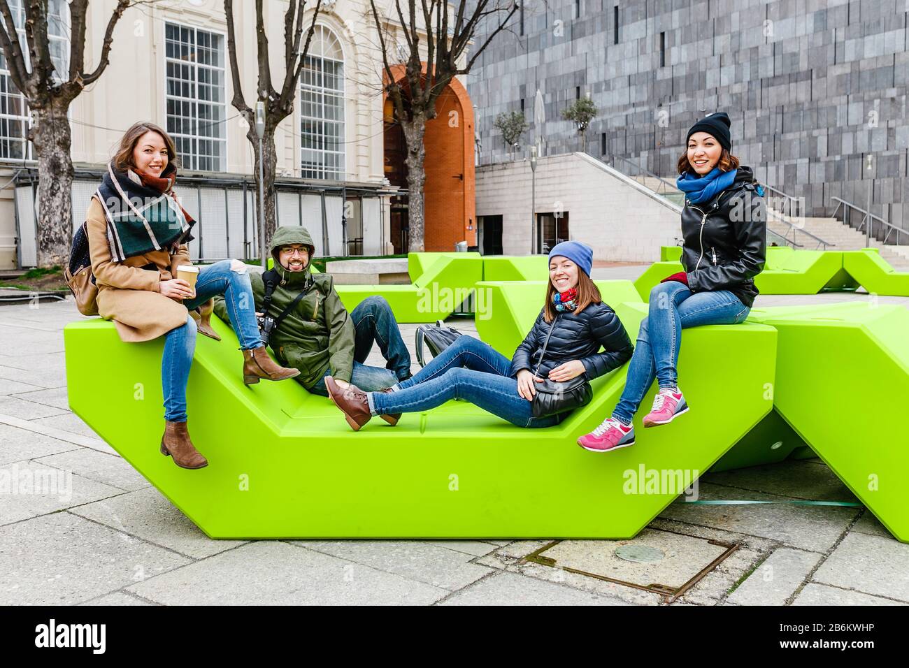 Eine Gruppe von Freunden, die Spaß haben und auf der Bank im Park in Wien sitzen Stockfoto