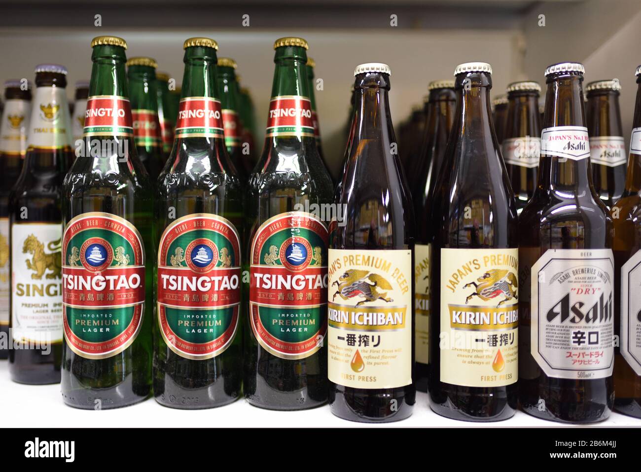 Flaschen Asiatischer Biere, darunter thailändisches Singha, chinesisches Tsingtao und japanisches Kirin Ichiban und Asahi-Bier auf dem Display im asiatischen oder chinesischen Supermarkt Stockfoto