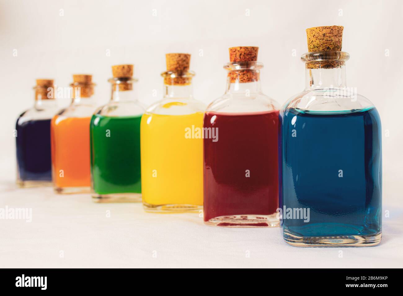 Sechs Glasflaschen in Perspektive mit Primär- und Sekundärfarben blau rot gelb grün orange violett Stockfoto